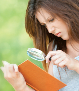 A woman using a magnifying glass to read a book