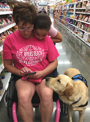 Photo of Service-dog Jaeger watching Darbi and her daughter Sami calculate their purchases