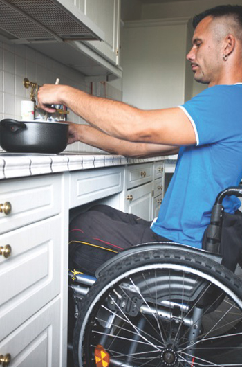 Photo of a man in a wheelchair cooking on the stove