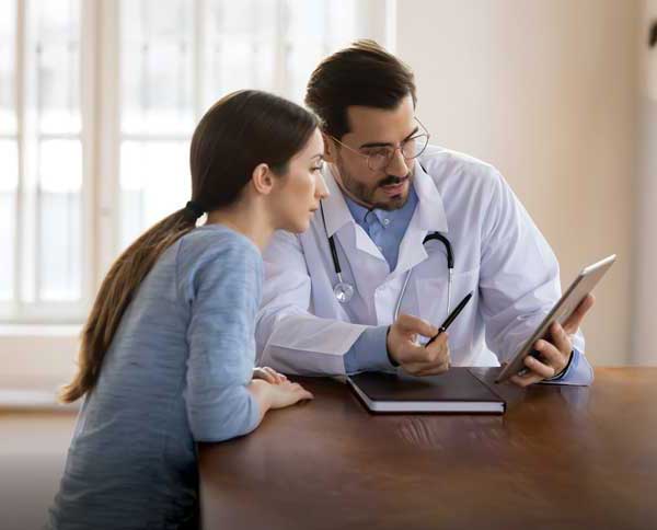 doctor on ipad Doctor and patient reviewing a plan width=
